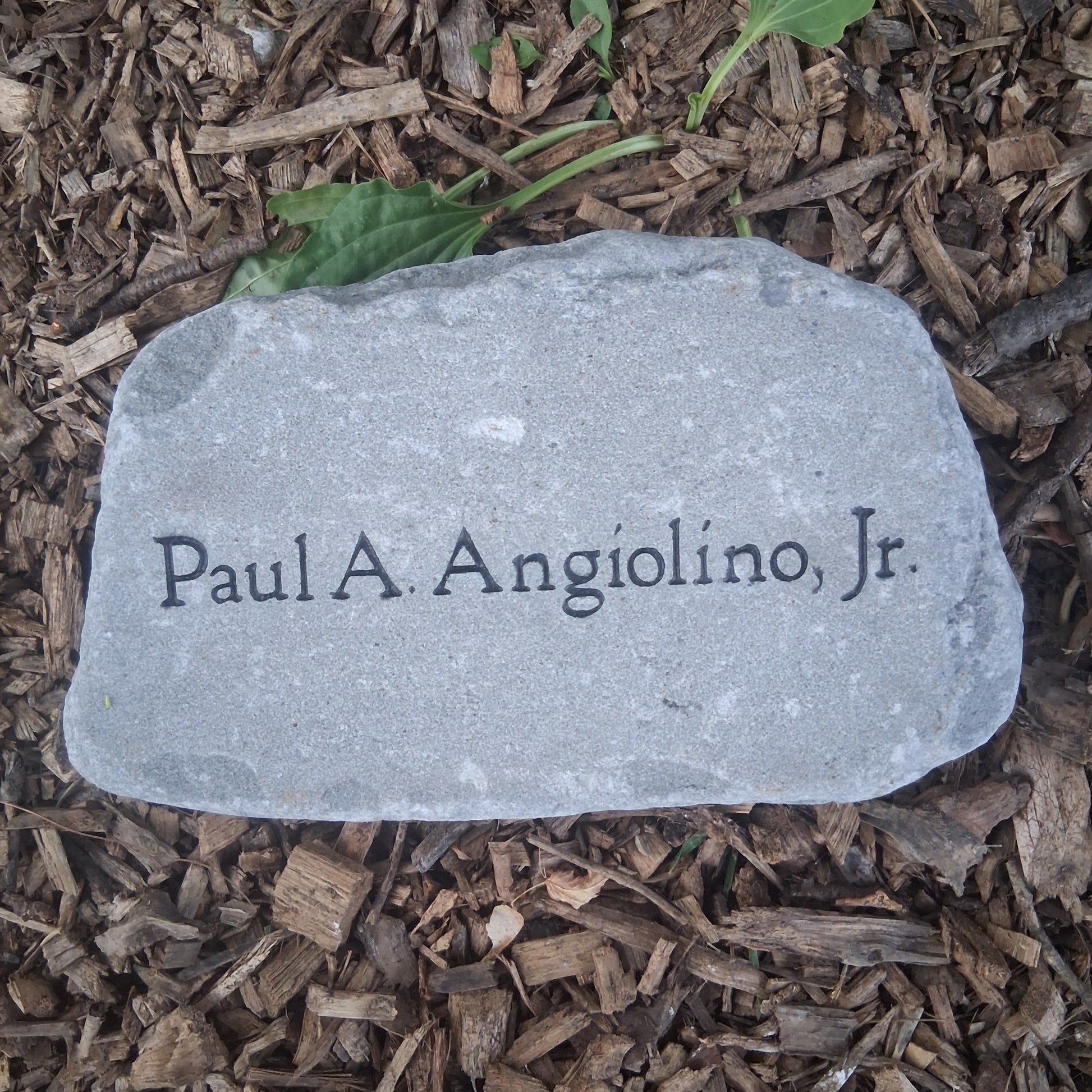 A personalized gray memorial garden stone engraved with a name 