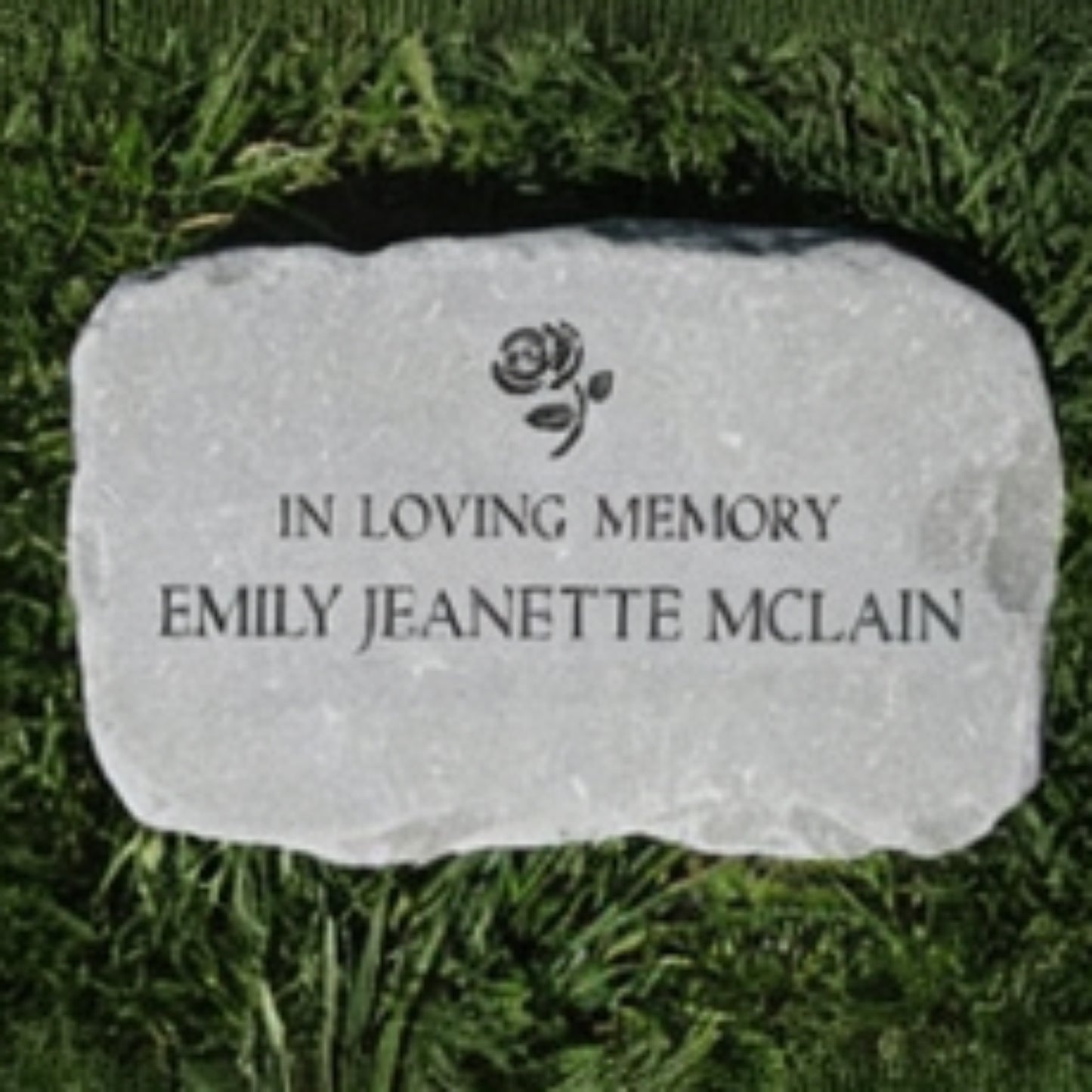 A personalized garden memorial marker engraved with a rose icon and the text 'IN LOVING MEMORY', placed on green grass.