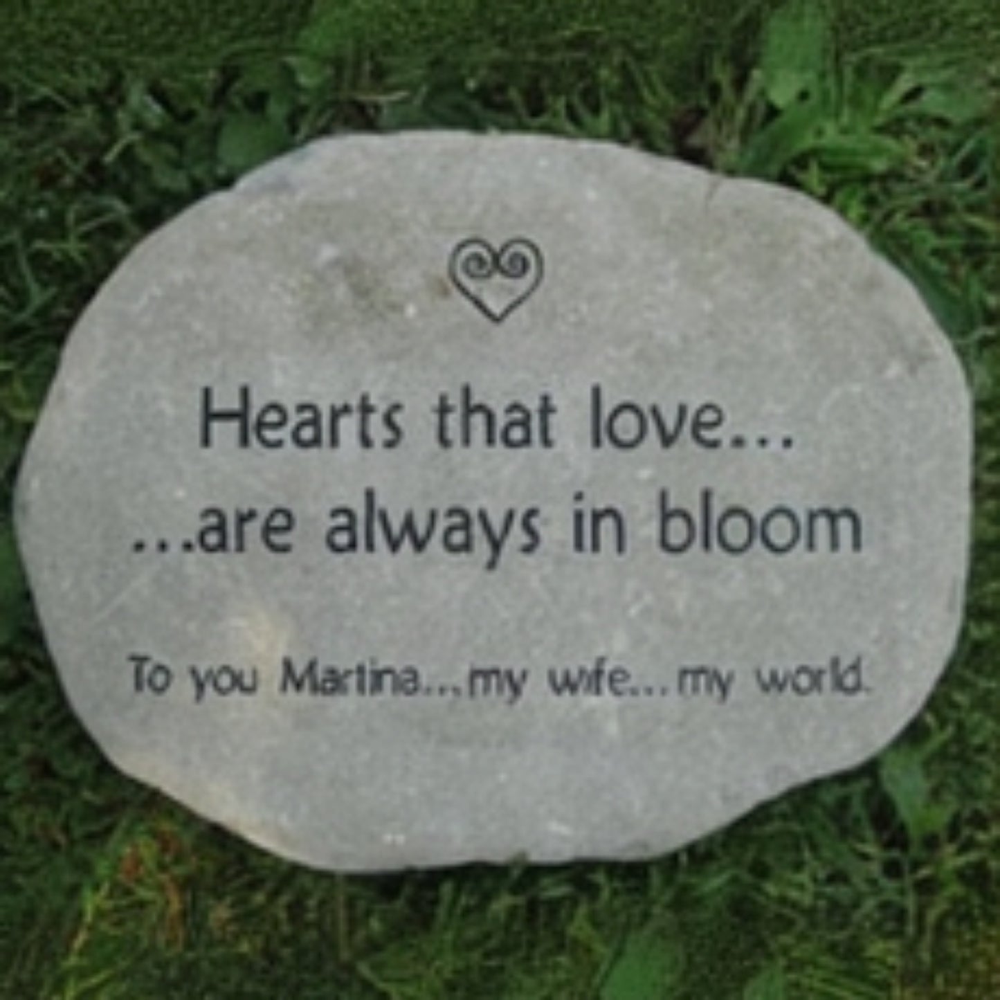 A round brown garden stone engraved with the words 'Hearts that love.