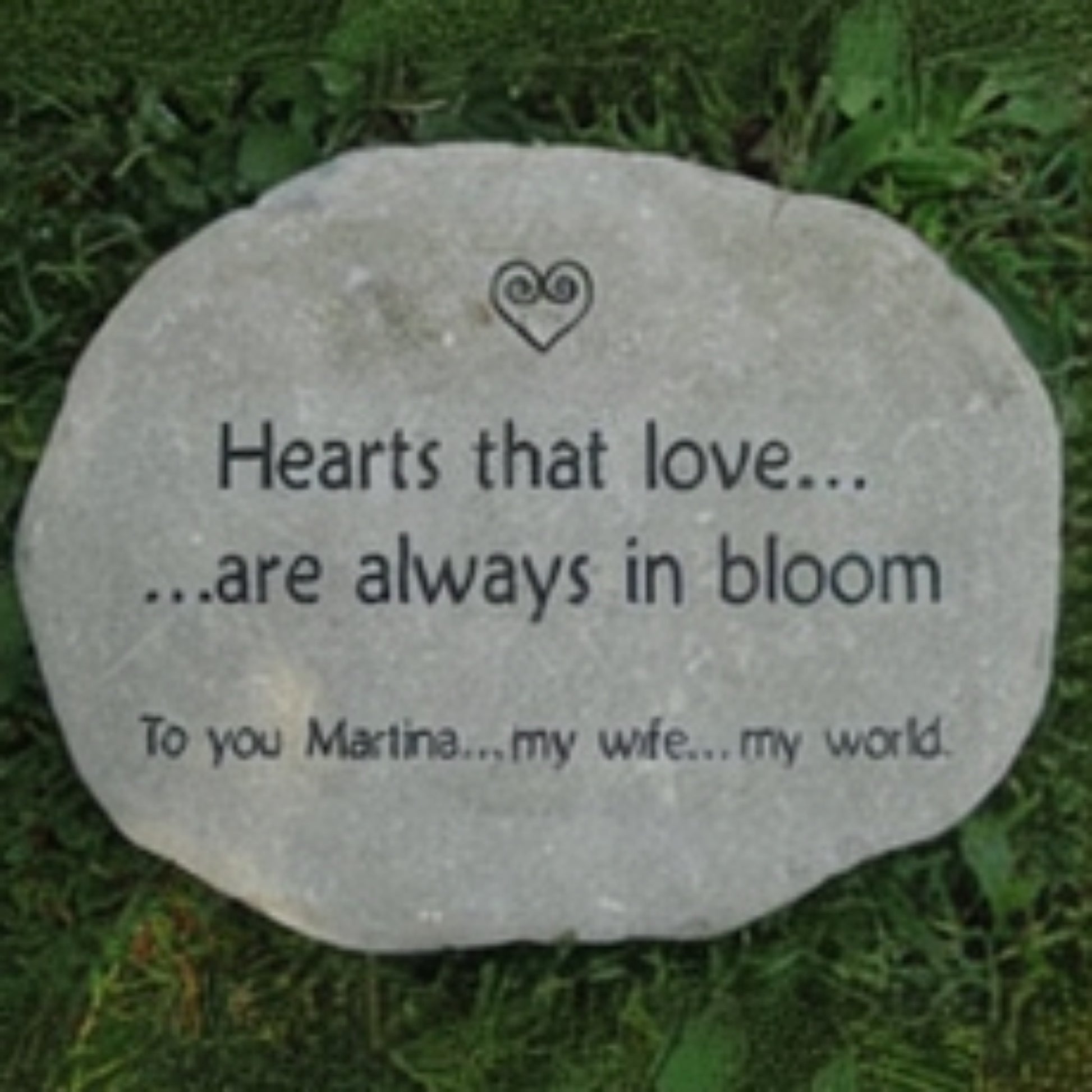 A round brown garden stone engraved with the words 'Hearts that love.